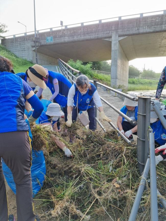 민락천 산책로 진입계단 난간에 걸린 수초를 제거하는 송산3동 통장협의회 회원들